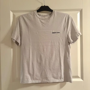 T-shirt från Arigato - T-shirt från Axel Arigato med enkel svart text 'ARIGATO ©2014' tryckt på bröstet. Klassisk rund halsringning och korta ärmar. Perfekt för en clean och stilren look.