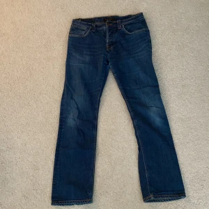 Blåa Nudie Jeans - Säljer de här Jeansen. De har blivit använda ett par gånger och tvättas ett par gånger. Men färgen är fortfarande djupt blå och har inte mycket täcken av användning.