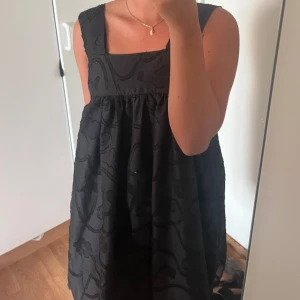 Egensydd klänning med broderade detaljer - Säljer en hemmagjord super fin klänning med breda axelband och fyrkantig ringning. Klänningen har ett löst fall och ett tyg  med broderade blommor och mönster.