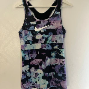 Mönstrad träningstopp från Nike - Säljer en färgglad träningstopp från Nike med Dri-FIT-material. Ärmlös modell med brottarrygg