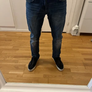 Mörkblå jeans från Armani, regular fit - Snygga mörkblå jeans från Armani med klassisk femficksdesign och silverfärgad logga på bakfickan. Jeansen har normal passform och raka ben, perfekt till vardags. Materialet är slitstarkt denim och färgen är något tvättad för en cool look.