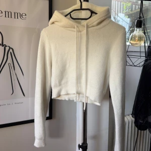 Vit stickad Huvtröja från Zara - Mysig vit croppad hoodie med långa ärmar och huva. Tröjan är stickad och har dragsko vid halsen. Perfekt för lager-på-lager i storlek S. Har sminkfläkar vid halsringningen men annars bra skick