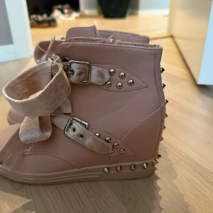 Rosa wedgesneakers  - Ljusrosa wedge sneakers med stora sammetsband som snörning och dekorativa silverfärgade nitar längs sidorna och bak. Jätte söta och bekväma! Passar superbra till kjol på sommarn! Säljer då jag har två likadana par💗