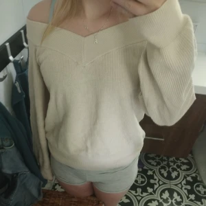 Beige stickad tröja - Fin stickad tröja med en off shoulderlook. Använd ett fåtal gånger. Är en L men skulle själv beskriva den som en S/M i storlek 