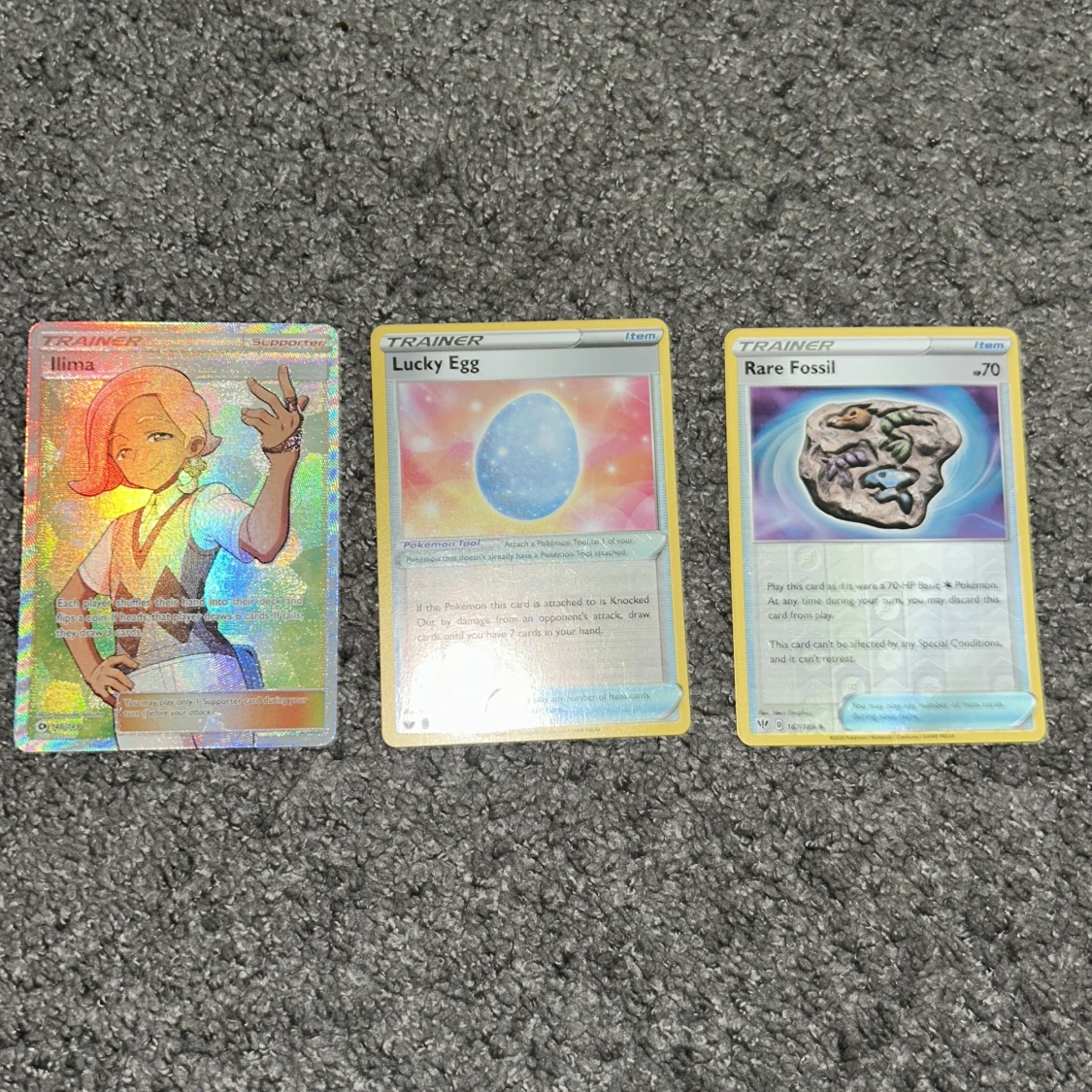 Pokémon Trainerkort: Ilima, Lucky Egg, Rare Fossil