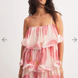 Jättefin volangklänning med smala axelband - Säljer en superfin rosa klänning med blommigt mönster och volangdetaljer. Klänningen har tunna axelband och är tillverkad i ett lätt, plisserat material som ger ett luftigt intryck. Perfekt för sommarens alla tillfällen! Endast testad💕