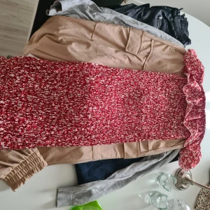 Röd blommig  - Säljer en röd klänning med vitt blommönster och volangdetaljer längs kanten. Klänningen har och är ärmlös, perfekt för sommarens tillfällen. Materialet känns lätt och luftigt.