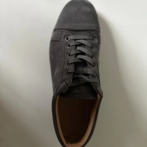 Mörkgråa louboutin  - Säljer ett par stilrena mörkgråa sneakers med rund tå och platt sula. Skorna har ovandel i mocka och klassisk snörning framtill. Perfekta för dig som gillar en enkel och clean look. (Använda) Därför billigt 