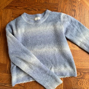 Ljusblå stickad tröja från Pull&Bear - Mysig ljusblå stickad tröja från Pull&Bear med rund halsringning. Tröjan har en mjuk, lite luddig yta och långa ärmar. Den har cool färgombre. Lite nopprig men syns inte. Perfekt för kyligare dagar och enkel att matcha med jeans eller kjol. Storlek L men är liten i storleken och sitter som XS