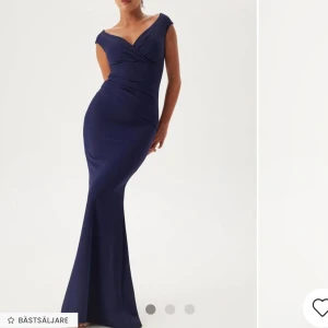 Marinblå långklänning - Elegant marinblå långklänning med v-ringad design och omlott-detaljer. Klänningen har en figurnära passform och korta ärmar, perfekt för en stilfull kväll. Klänningen är endast använd vid 1 tillfälle💗