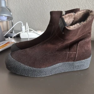 Bruna boots från Canada Snow - Snygga bruna boots från Canada Snow i mocka med dragkedja på sidan. De har en robust grå sula och är fodrade med mjukt pälsmaterial för extra värme. Perfekta för kyliga dagar. Kommer med låda. Storlek 42