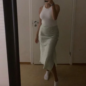 Ljusgrön blommig kjol från BikBok - Säljer en elegant ljusgrön kjol från BikBok i storlek XS. Kjolen har ett blommönster och är i en lång modell. Perfekt för en stilren look. 