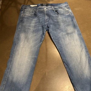 Replay Anbass Jeans - Hej, säljer dessa riktigt snygga Replay Anbass jeans. Jeansen är i väldigt fint skick. Jeansen är i W33 men om ni undrar något mått eller något annat så är det bara att skriva. Jeansen har en liten defekt på rumpan men det är lagat. Priset på dessa jeansen ligger på 1800kr i nypris.