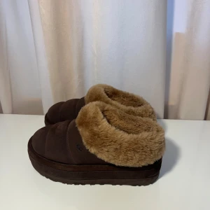 UGG skor - UGG skor i ljusbrun färg. Perfekta för att hålla fötterna varma under kalla dagar. De har en robust sula som ger bra grepp inomhus.