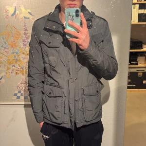 Woolrich field jacka - Säljer en grå jacka från Woolrich. Jackan har en stilren design och är perfekt nu inför våren. Väldigt fint skick strl M. Nypris runt 4000 kr