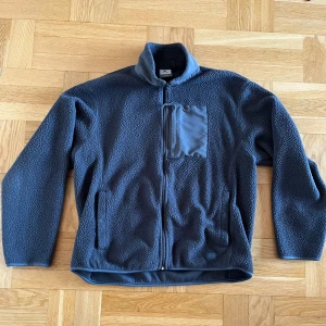 Mörkgrå fleecejacka från McKinley - Säljer en mörkgrå fleecejacka från McKinley i storlek XL. Jackan har en dragkedja framtill och en praktisk bröstficka med dragkedja. Perfekt för kyliga dagar med sin mjuka och varma fleece.