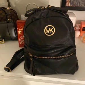 Svart ryggsäck från Michael Kors - Snygg svart ryggsäck från Michael Kors i skinn med guldfärgade detaljer och dragkedja. Rymlig insida med flera fack för enkel organisering. Använd fåtal gånger, skriv för mer information!😊💞