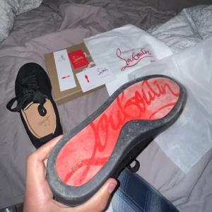 Svarta sneakers från Christian Louboutin - Snygga svarta sneakers från Christian Louboutin med den ikoniska röda sulan. Skorna har snörning och är perfekta för att ge en lyxig touch till din stil. Levereras med originalförpackning och påse.