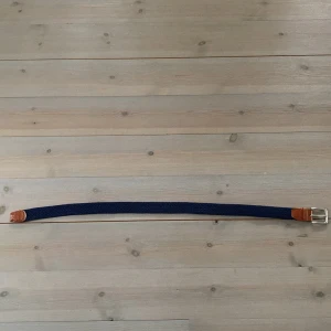 Blått bälte från Jack & Jones - Snyggt marinblått flätat bälte från Jack & Jones med bruna skinn-detaljer och ett stilrent silverfärgat spänne. Perfekt för att ge en casual look och en extra touch. Bältet är flätat vilket ger det en unik textur och känsla. Köpt för 400.