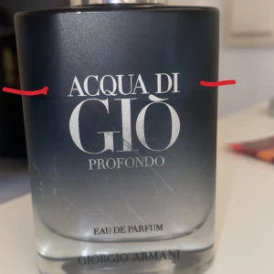 Acqua di Giò Profondo Eau de Parfum - Säljer en elegant flaska av Acqua di Giò Profondo Eau de Parfum från Giorgio Armani. Flaskan har en stilren design i mörkblått glas som övergår till transparent vid botten. Perfekt för den som söker en fräsch och marin doft.