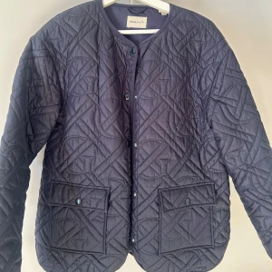 Mörkblå quiltad jacka från GANT - Säljer en snygg mörkblå tunn jacka från GANT. Jackan har en rund halsringning och knäpps med knappar framtill. Den har två fickor på framsidan. Perfekt till våren! Storlek 170 men passa mig som är cirka 170 och brukar ha S i jackor vanligtvis. 🩷