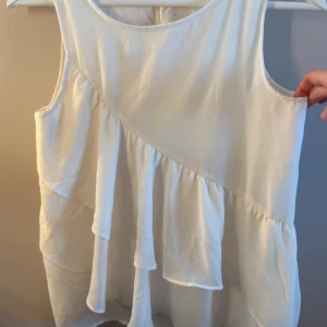 Vit ärmlös blus - säljer denna vita blus från hm, jättefin men används inte så därför jag säljer den!