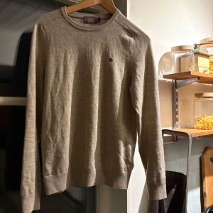 Beige tröja från Morris - Säljer en stilren beige tröja från Morris i 100% merinoull. Tröjan har en liten broderad logga på bröstet och ribbade muddar vid ärmslut och nederkant. Perfekt för kyligare dagar. Köpt för 1599 på Morris butik och passar dig som är 173-180cm lång med funkar för kortare. Säljer tröjan otroligt billigt för får ingen användning av den och den har inga skråmor eller någonting. Tveka inte på att höra av er vid eventuella frågor!!!!!