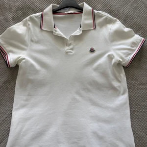 Vit pikétröja från Moncler - En vit pikétröja från moncler med storlek M. Är i väldigt bra skick och inga fel på den alls. Köpt från Care Of Carl och kvitto finns. 