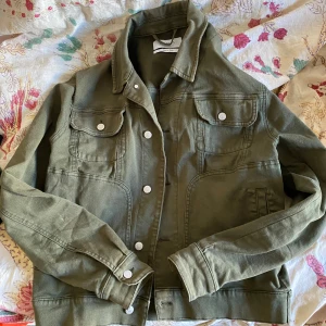 Olivgrön jacka från Les Deux - Säljer en snygg olivgrön jacka från Les Deux. Jackan har en klassisk design med knappar framtill och två bröstfickor med fickor. Storlek L men sitter mer som M. 