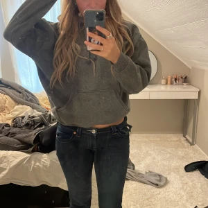 Grå hoodie - Säljer en grå hoodie med en avslappnad passform. Den har en klassisk känguruficka och justerbar huva med dragsko. Perfekt för en bekväm och stilren look.