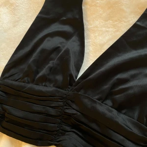 Svart topp från BikBok - Snygg svart topp från BikBok med knappar och veckade detaljer.. Öppen rygg. Aldrig använt. 