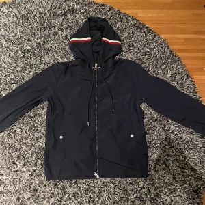 Moncler windbreaker - Snygg svart vindjacka från Moncler med huva och dragkedja. Jackan har långa ärmar och en stilren design med Moncler-logga på ärmen. Perfekt för blåsiga dagar. Byter gärna!!