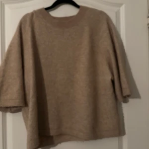 Beige tröja med trekvartsärm - Säljer en mysig beige tröja med trekvartsärm. Perfekt för kyligare dagar och har en avslappnad passform. Tröjan är enkel och stilren, vilket gör den lätt att matcha med olika outfits. Från and other stories