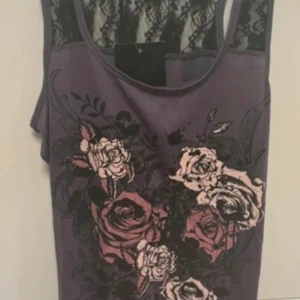 Lila linne med spetsdetaljer  - Säljer ett snyggt lila linne från Takko Fashion med blommigt mönster och spetsdetaljer på ryggen. Perfekt för att ge en romantisk touch till din outfit. Linnet har en avslappnad passform och ärmlös design.