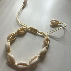Armband med snäckor - Snyggt armband med vit/beiga snäckor och justerbart band. Köpt i Cypern. Ingen snäcka borta eller skadad.