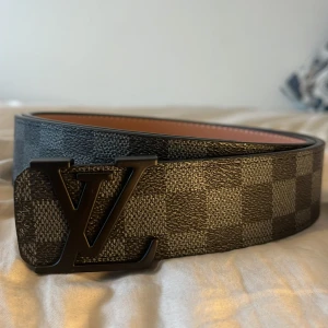 Svart och grått rutigt bälte från Luviton - Snyggt bälte från Luviton med ett rutigt mönster i svart och grått. Bältet har en stilren Luviton spänne i svart metall. Perfekt för att ge din outfit en lyxig och stilig stil. Speciellt till gråa jeans Men funkar såklart till alla jeans. Otroligt bekväm och stabil. Trendig och snygg. Nästan helt oanvänd och helt fräsch. Serveras med en 4 cm mettalpinne. PRISET KAN DISKUTERAS.