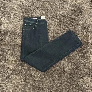 Jacob cohen jeans - Snygga mörkblå jeans från Jacob Cohën med klassisk femficksdesign och knappgylf. Jeansen har en läderpatch med logotyp baktill och är tillverkade i ett högkvalitativt denimtyg. 32/32 men skulle mer säga att dem är 30/32 nypris 4000