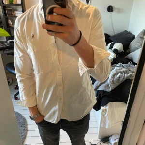 Vit skjorta från Ralph Lauren - Säljer en stilren vit skjorta från Ralph Lauren i slim fit. Skjortan har långa ärmar och är dekorerad med det klassiska broderade logotypen på bröstet. Perfekt för en elegant look.