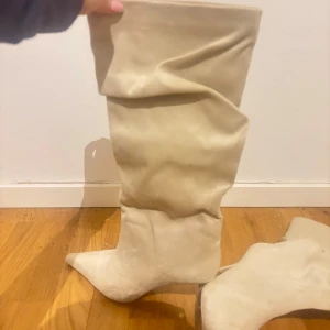 Beige stövlar med spetsig tå - Snygga beige stövlar i mocka med spetsig tå och hög skaft. Perfekta för att ge en stilren touch till din outfit i sommar. De har en elegant design som passar bra till olika tillfällen. Helt nya, säljer för att dem tyvärr var för stora☹️