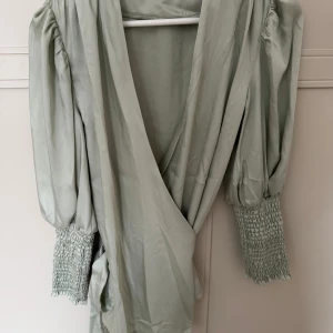 Omlottblus By Malina - Denna vackra blus är helt oanvänd, bara prislappen borttagen. Går att knyta på flera olika sätt. 