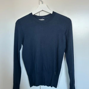 Mörkblå tröja från Holly & Whyte - Snygg mörkblå tröja från Holly & Whyte by Lindex. Tröjan har en klassisk rund halsringning och långa ärmar med fina guldknappar på.❤️