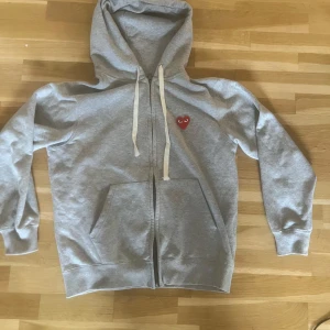 Grå hoodie från Comme des Garçons - Säljer en grå hoodie från Comme des Garçons med dragkedja och huva. Med storlek S men skulle säga att även passar storlek M. Den är i hyfsat bra skick. Nypris: 2000kr 