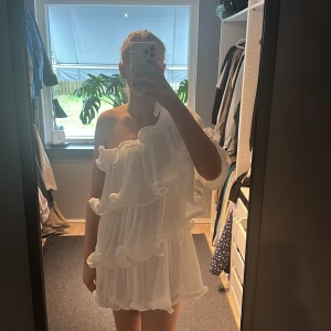 Vit klänning med volanger från NA-KD - Säljer en superfin vit klänning från NA-KD med volanger. Den är axelbandslös och har en luftig design som ger en romantisk känsla. Perfekt för sommarens alla tillfällen. 💫