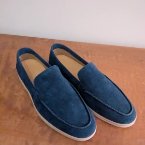 Loafers mocka navy - Snygga blå loafers i mocka med en stilren design. De har en bekväm sula och är perfekta för en avslappnad men ändå elegant look.                          Helt oanvända