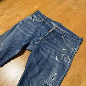 Blå dsquared2 Jeans - Snygga blå jeans från Dsquared2 med slitna detaljer och unik broderad ficka. Väldigt bra skick, inga skador. Storlek 50 | vårt pris: endast 649kr!! | skriv privat angående eventuella frågor eller funderingar.