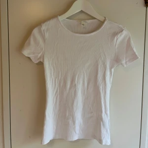 Vit ribbad kortärmad topp - Enkel och fräsch vit ribbad topp med korta ärmar och rund hals. Perfekt basplagg i garderoben, lätt att matcha med allt. Mjuk och stretchig känsla som sitter snyggt på kroppen.