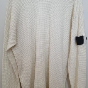 Vit stickad tröja Stone Island - Vit stickad tröja från Stone Island med klassisk svart logotyp-patch på ärmen. Tröjan har långärmad design och är tillverkad i ett grovt, strukturerat stickat material som ger en cool och avslappnad vibe. Perfekt för lager-på-lager under höst och vinter.