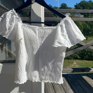 Vit  blus med puffärm❤️ - Supersöt vit blus med smockad kropp och vida puffärmar. Offshoulder-modell med stretchig resår upptill och volangkant nertill. Perfekt för sommarens alla tillfällen, ger en romantisk och trendig vibe. Tunn och luftig, passar dig som gillar en feminin stil. Tröjan är superskön och stretchig💕😃 Använd två gånger, storlek 170 men passar nog XS- M
