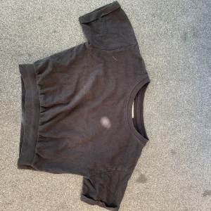 Svart kortärmad tröja i bomull - En basic svart tröja i mjuk bomull med korta ärmar och bred ribbad mudd nedtill. Enkel och stilren modell som passar perfekt till jeans eller kjol. Rund halsringning och avslappnad passform.