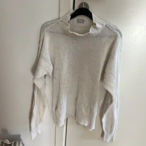 Vit stickad tröja med halvpolo, Daniels - Vit stickad tröja från Daniels i storlek M. Tröjan har en halvpolo och diskret strukturmönster i stickningen. Långärmad modell med ribbade muddar vid ärmslut och nederkant. Perfekt för lager-på-lager och chill stil. Speciellt till hösten🥰